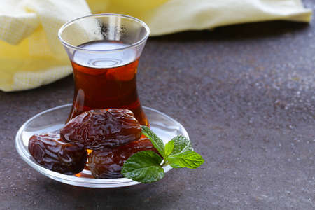 Turkish tea in traditional glass with sweet datesの写真素材