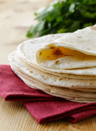 stack of homemade whole wheat flour tortillas on a wooden table