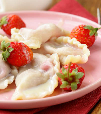 dumplings with berries and cream sauce served with fresh strawberriesの写真素材