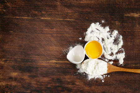 wooden baking background with raw eggs and flourの写真素材
