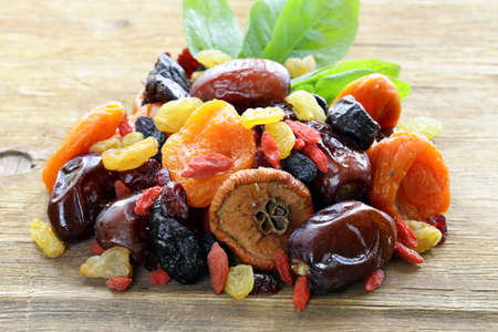 Assorted dried fruits raisins apricots figs prunes goji cranberries on a wooden background Assorted dried fruits raisins apricots figs prunes goji cranberries on a wooden background
