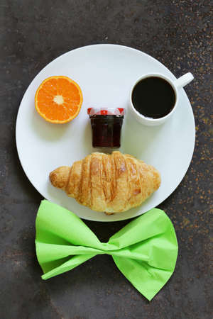 Breakfast serving funny face on the plate jam croissant orange and coffeeの写真素材