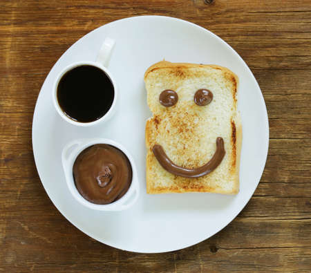 Breakfast serving funny face on the plate toast chocolate spread and coffeeの写真素材