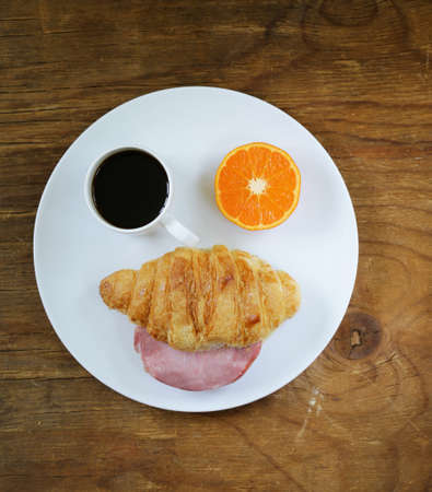 Breakfast serving funny face on the plate croissant with ham orange and coffeeの写真素材