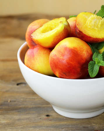 ripe organic peaches with mint leaves on a wooden tableの写真素材