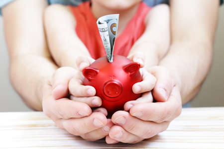 close up of father and son hands holding red piggy bankの写真素材