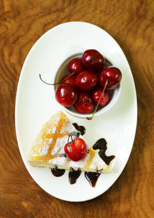 homemade cheesecake with powdered sugar and cherry on a white plate