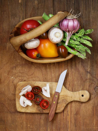 asparagus, tomatoes, garlic, mushrooms in a basket on a wooden backgroundの写真素材