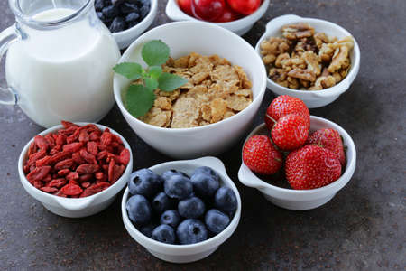 set of ingredients for a healthy food breakfast - muesli, fresh and dried fruit, nuts, goji berries