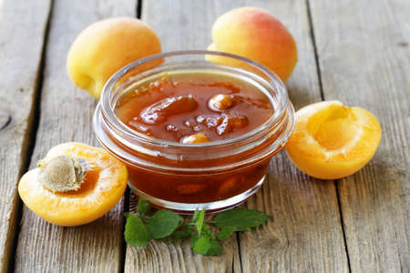 Apricot peach jam in a glass jar on a wooden backgroundの写真素材