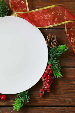 Christmas wooden background with fir branches, decoration and white plateの写真素材
