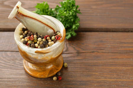 peppercorns in a stone mortar on a wooden tableの写真素材