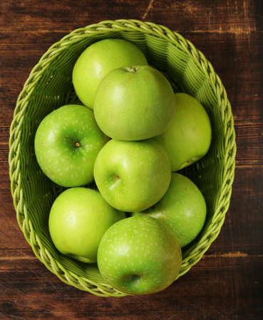 Fresh organic green apples in a basket on a wooden backgroundの写真素材