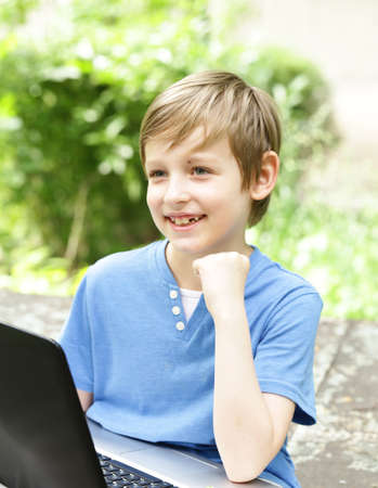 boy playing on the computer (laptop) in a park