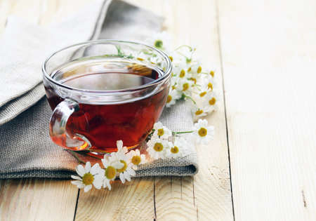 glass cup with tea and chamomile on a wooden backgroundの写真素材