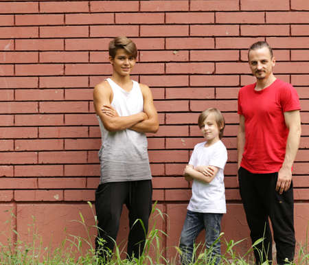 family, father and two sons having fun and posing brick wall background