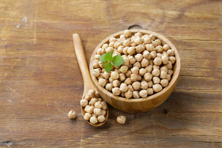 raw chickpeas in a wooden bowl on the tableの写真素材