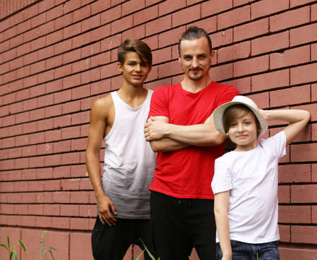 family, father and two sons having fun and posing brick wall backgroundの写真素材