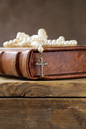old book (bible) and the Christian symbol cross on pearl necklace