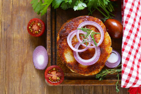 fried cutlets with herbs and onions on a wooden boardの写真素材