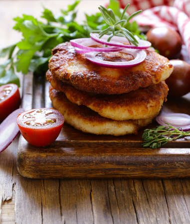 fried cutlets with herbs and onions on a wooden boardの写真素材