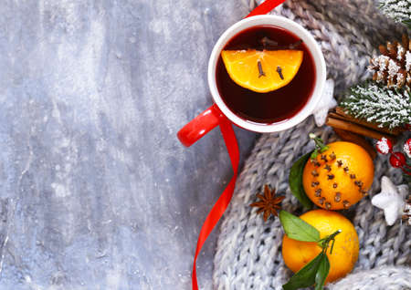 Traditional winter beverage mulled wine. Christmas drink. Gray background with knitted scarf