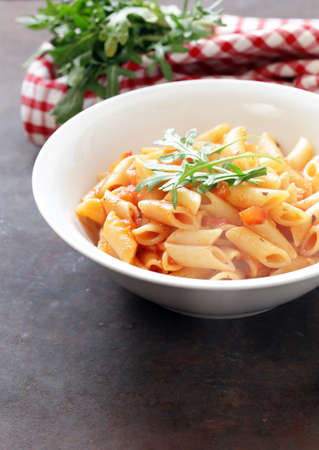 penne pasta with tomato sauce in a white plateの写真素材