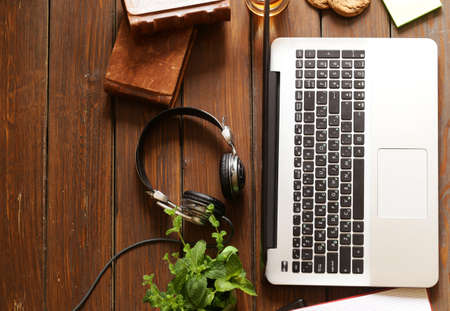 Wooden desktop with laptop, books and headphonesの写真素材