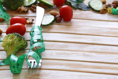 Diet concept - fork with measuring tape on a wooden tableの写真素材