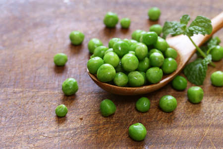 Fresh green peas in a wooden spoonの写真素材