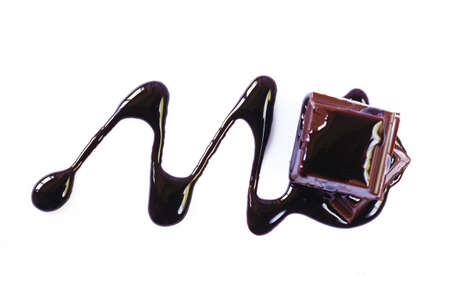 Pieces of dark chocolate and syrup on a white backgroundの写真素材
