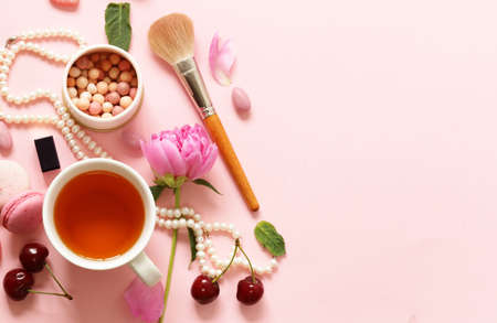 A cup of tea for a woman, macaroon, flowers and sweets on a pink backgroundの写真素材