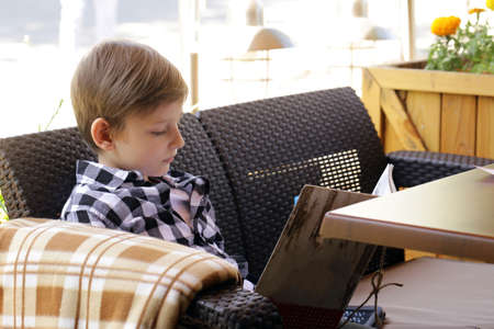 The boy in the cafe reads the menuの写真素材