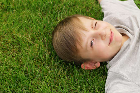 Cute young boy resting on the green grass - summer time, picnicの写真素材