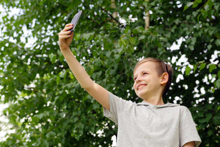 Cute blond boy doing selfie in a park outdoorsの写真素材