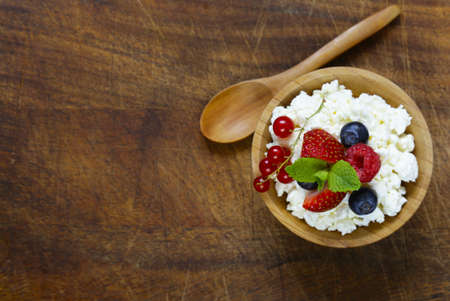 Organic cottage cheese with fresh berries in a wooden bowlの写真素材