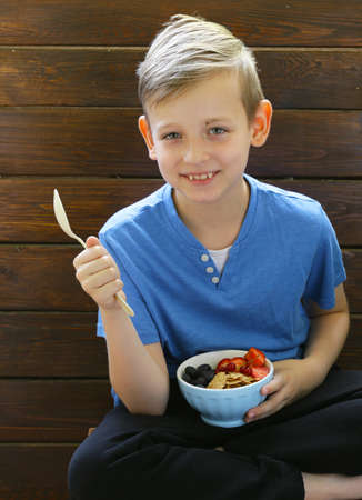 The boy has a healthy breakfast of cottage cheese and granola with berriesの写真素材