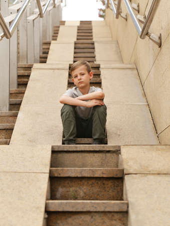 Sad boy sits on a large granite staircase - urban styleの写真素材