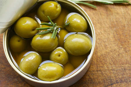 Organic canned green olives on a wooden tableの写真素材