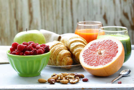 A healthy breakfast with croissants, fresh juice, nuts and raspberries
