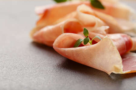 Parma ham thin slices on a black stone