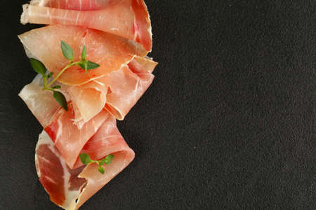 Parma ham thin slices on a black stoneの写真素材