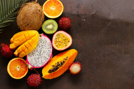 fresh tropical fruits - rambutan, papaya, kiwi, mango on a wooden backgroundの写真素材