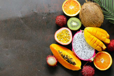 fresh tropical fruits - rambutan, papaya, kiwi, mango on a wooden backgroundの写真素材
