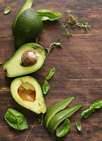 healthy avocado food and fragrant herbs on a wooden background