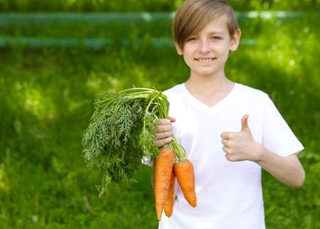 cute boy with organic carrots - healthy foodの写真素材
