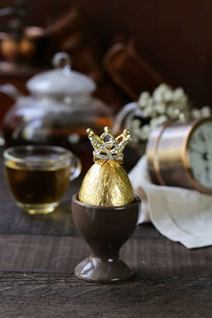 golden egg with a crown on a wooden tableの写真素材