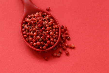 pink pepper peas in a spoon on a red backgroundの写真素材