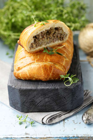 puff pastry pie with meat on a wooden boardの写真素材