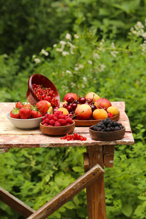 organic berries peaches, raspberries and strawberries on a wooden tableの写真素材